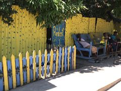 08B Relaxing on oversized chairs with a yellow metal fence behind on 2nd Street Trench Town Kingston Jamaica